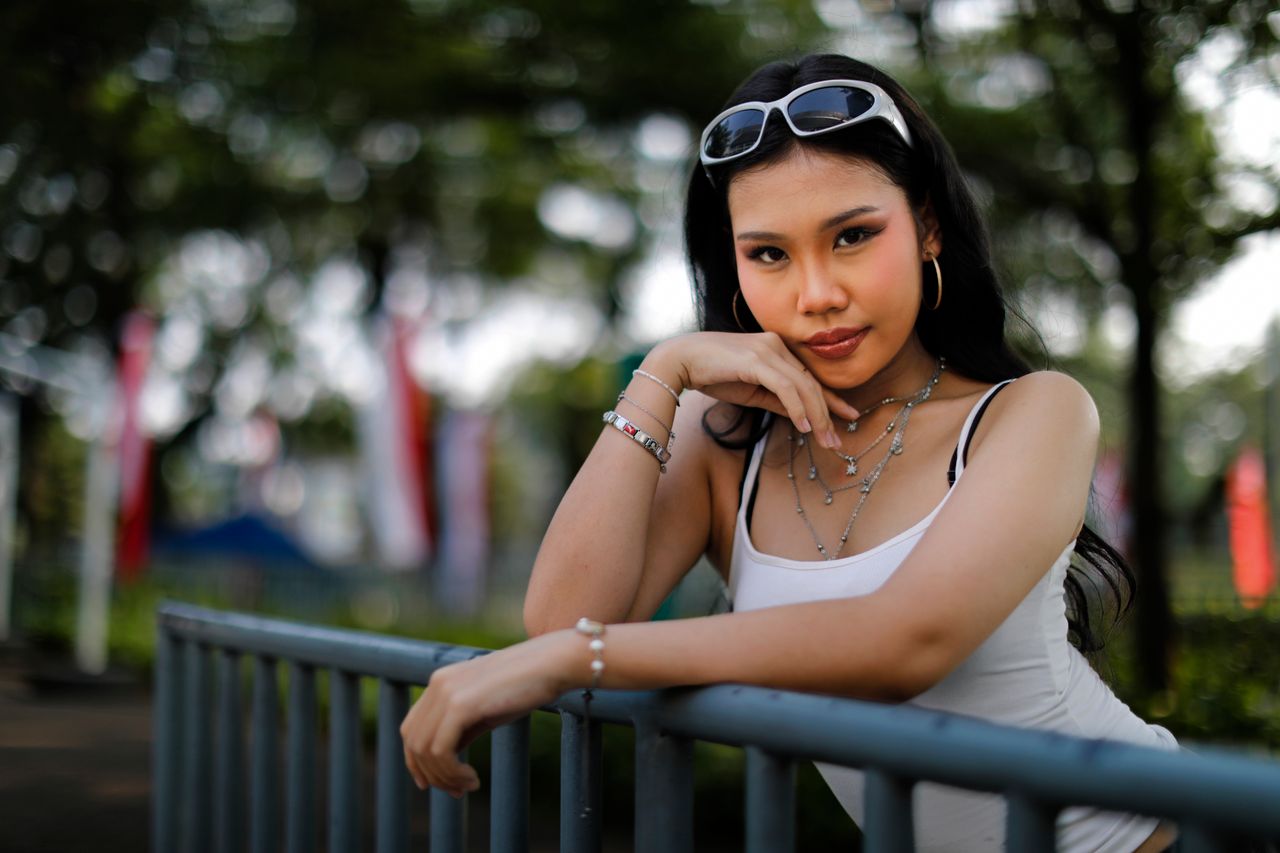 who-we-are A fashionable woman poses confidently in a park setting in Jakarta, Indonesia.