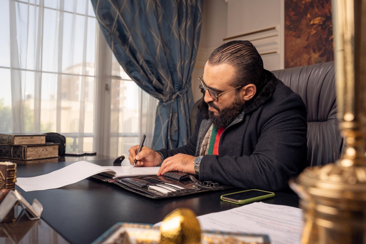 The Art of Drawing Readers In: Your attractive post title goes here Professional man writing at a desk in an elegant office setting, displaying concentration.